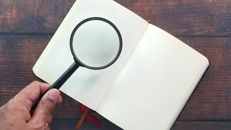 magnifying glass over an open notebook on a wooden table