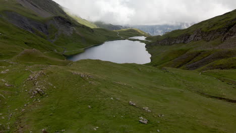 Aerial-front-approach-to-the-famous-lake-of-Bachalpsee-completely-in-the-shadows,-in-Switzerland