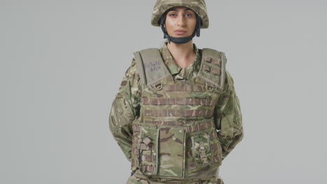 retrato de estudio de larga duración de una joven soldado en uniforme militar en un fondo plano