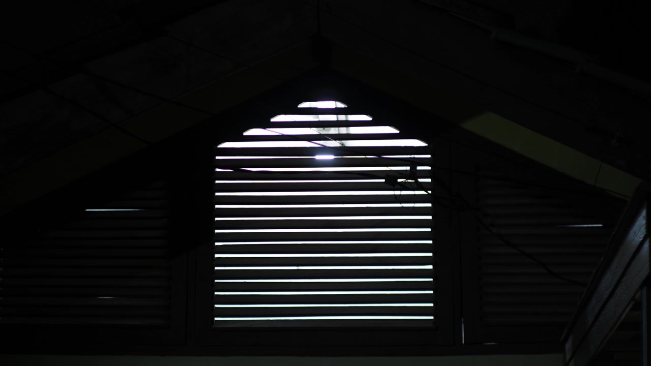 Night View of a Slatted Window With Bright Light Shining Through