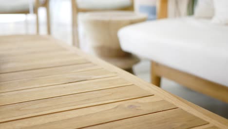 a woman's hand reaches for her phone on a wooden table in a living room