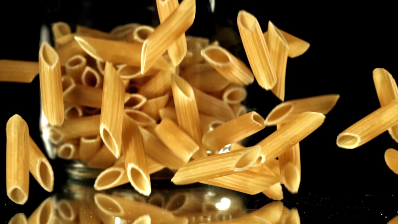 Penne crude che cadono e si disperdono su una superficie nera riflettente