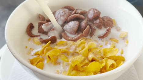 healthy breakfast concept - adding hot milk to a mixture of cereal and chocos