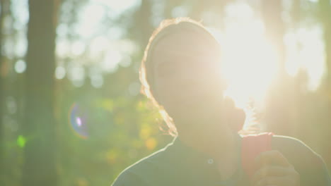 lady standing in forest with gentle smile, adjusting her bag while sunlight filters through trees, illuminating her hair with radiant glow, creating a warm and serene ambiance amidst nature