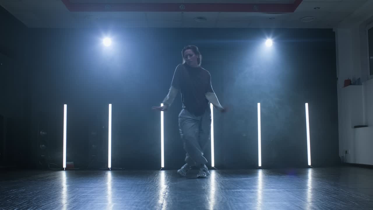 mujer joven bailando en el escenario con humo y reflector. silueta de mujer