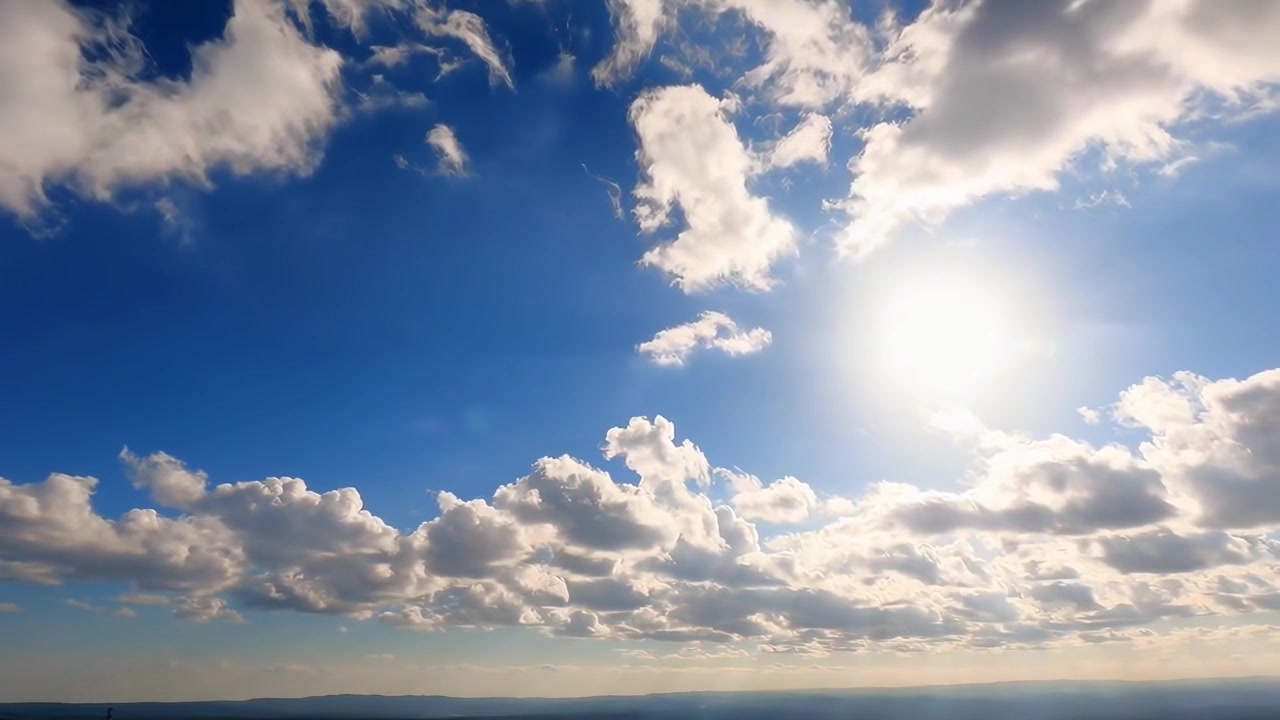Il sole splendente splende attraverso le nuvole bianche nel cielo blu