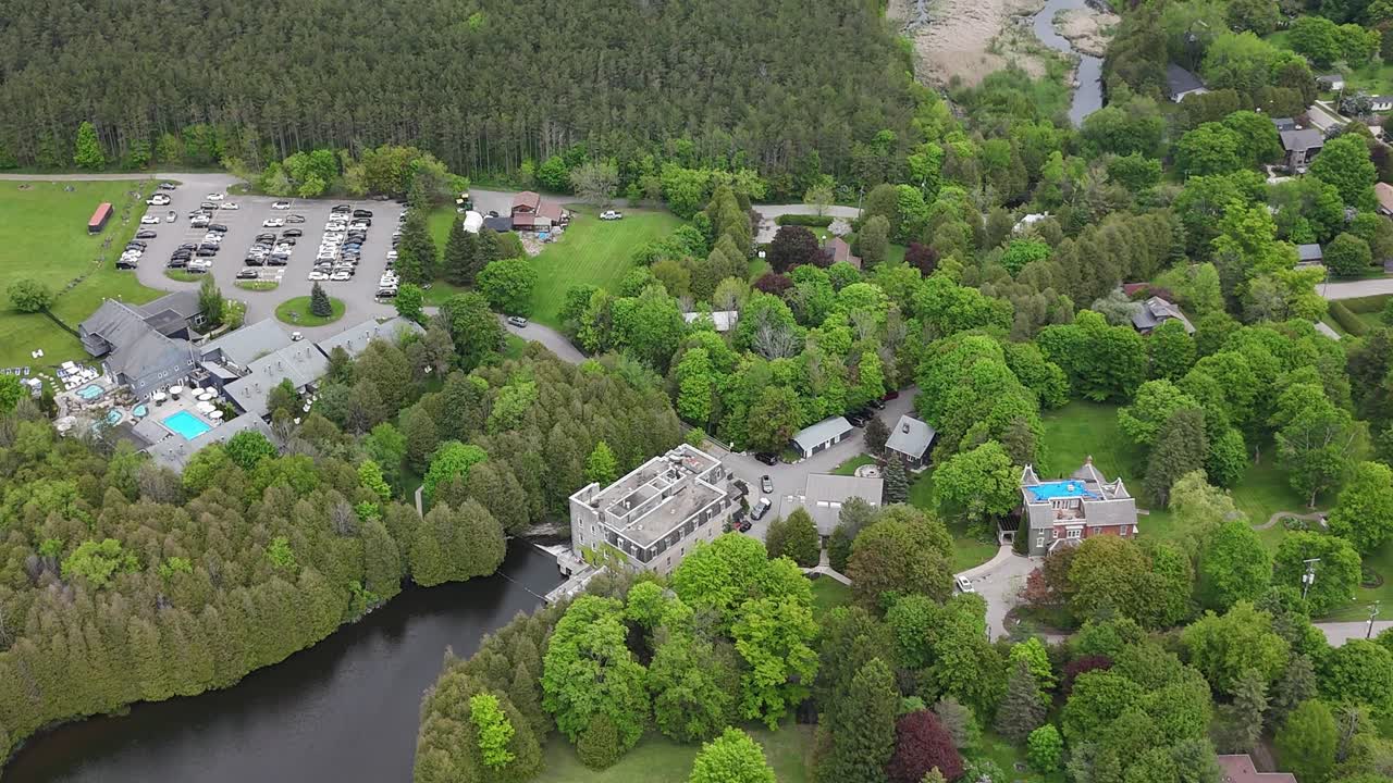 Aerial establishing pullback high angle of Millcroft Inn showing building, river, and natural landscape in Caledon