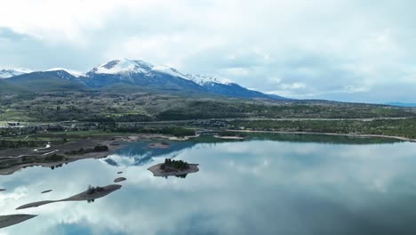 Dolly-Aéreo-Panorámico-Sobre-El-Lago-Que-Refleja-Montañas-Rocosas-Nevadas-En-Frisco-Colorado