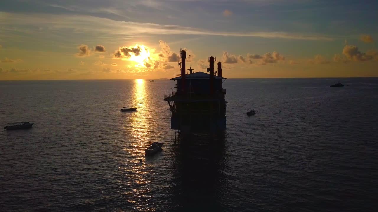 Betagende droneflyvning ved smuk solnedgang langs en olieboreplatform i Mabul, Malaysia.