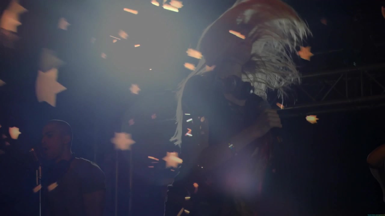 Foco iluminando a una cantante inclinándose hacia el micrófono, interpretando música con confeti de estrellas flotando.