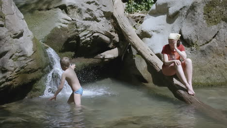 child and woman enjoying nature by a waterfall