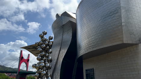 Tiro-Inclinado-Hacia-Arriba-Del-Moderno-Museo-Guggenheim-En-Arquitectura-De-Metal-Plateado-Durante-El-Día-Soleado,-Ciudad-De-Bilbao