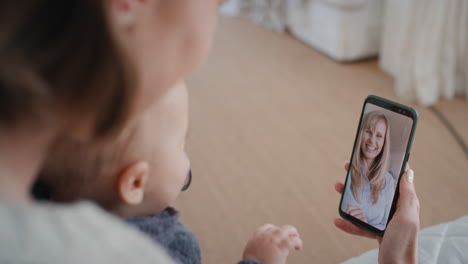 Mutter-Und-Baby-Nutzen-Smartphone-Und-Führen-Einen-Videochat-Mit-Der-Besten-Freundin,-Die-Dem-Kleinkind-Zuwinkt.-Glückliche-Mutter-Genießt-Es,-Den-Mutterschaftslebensstil-Auf-Dem-Handybildschirm-In-4K-Zu-Teilen