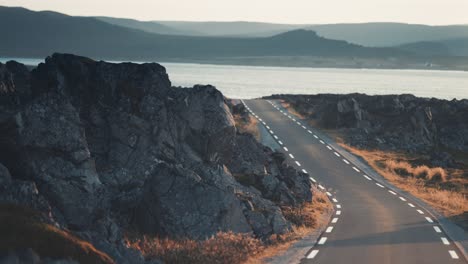 Driving-on-the-narrow-asphalt-road-between-the-rocky-outcrops-along-the-fjord-shores