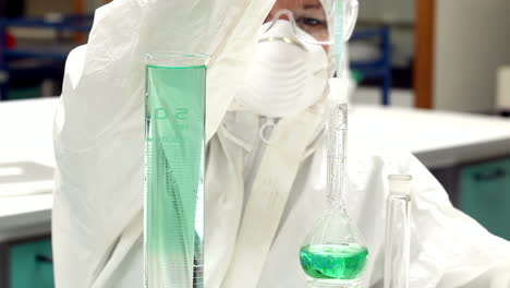 Science-student-in-protective-suit-working-with-green-chemicals