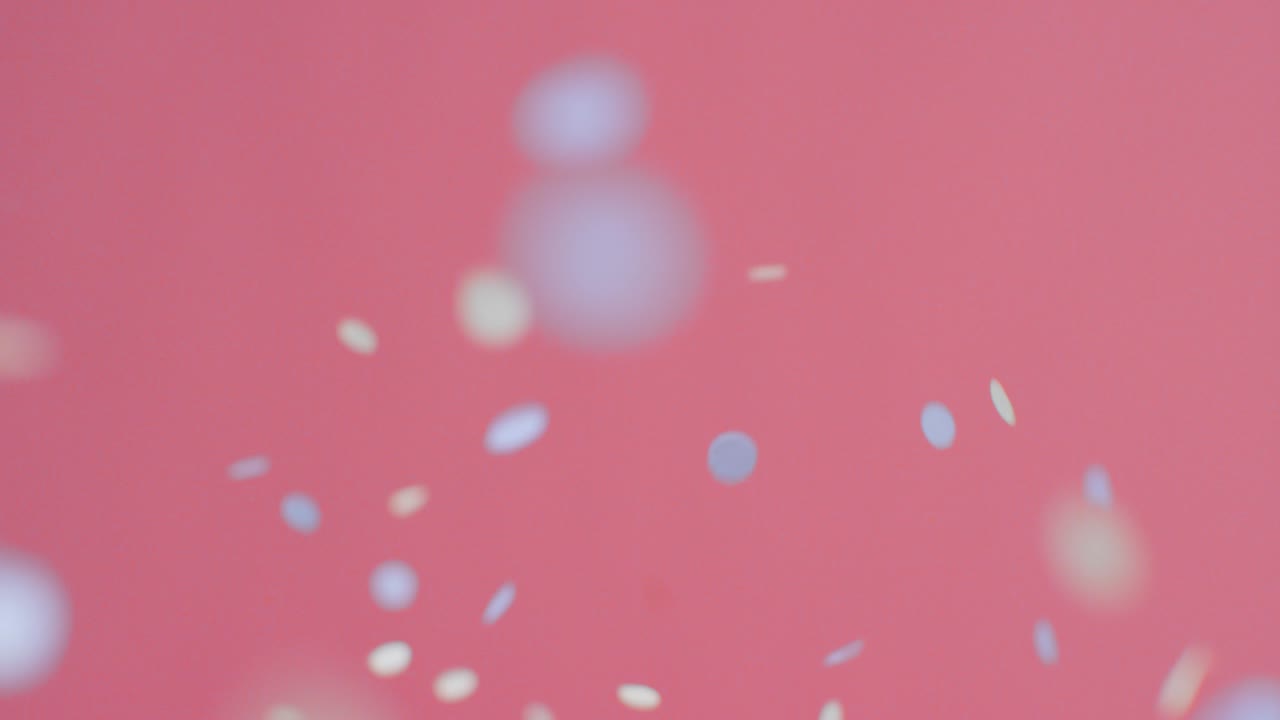 분홍색 배경에 떨어지는 파란색과 금색 색종이의 고정 샷