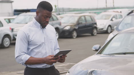 insurance loss adjuster with digital tablet inspecting damage to car from motor accident