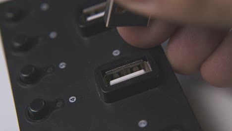 person takes off usb cable from hub on white surface macro