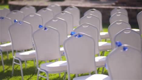 panning shot of empty white chairs in lawn at wedding ceremony