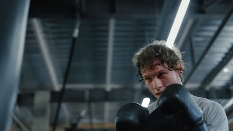 aggressive kickboxer hitting punching bag in fitness center. sportsman boxing