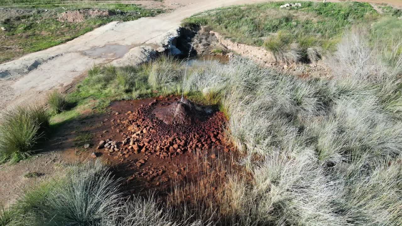 geyser at Fuendejalon Spain with spurting hot water and iron deposits.