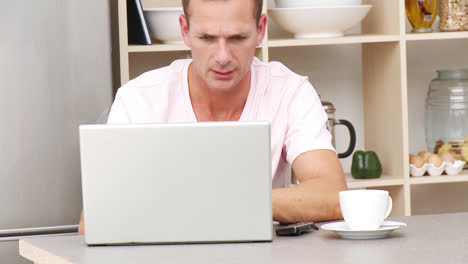 man working with a laptop in kitchen