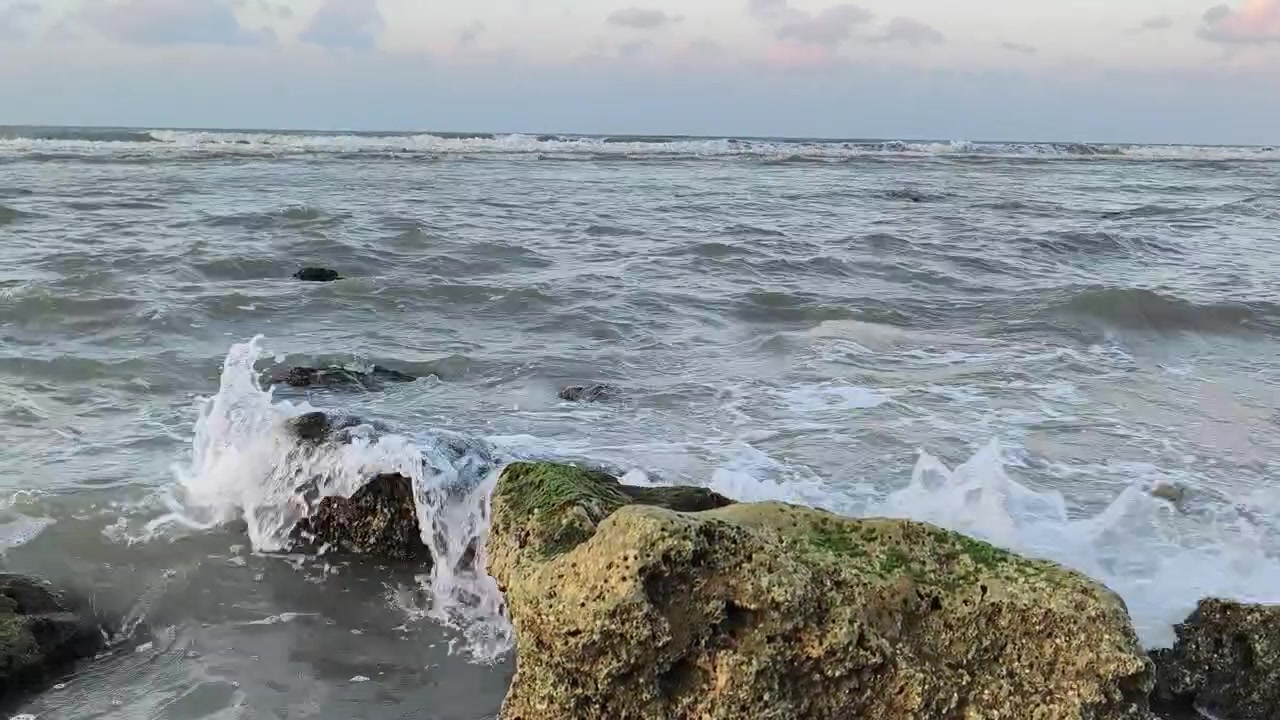 Onde dell'oceano che si infrangono contro rocce muschiose al tramonto