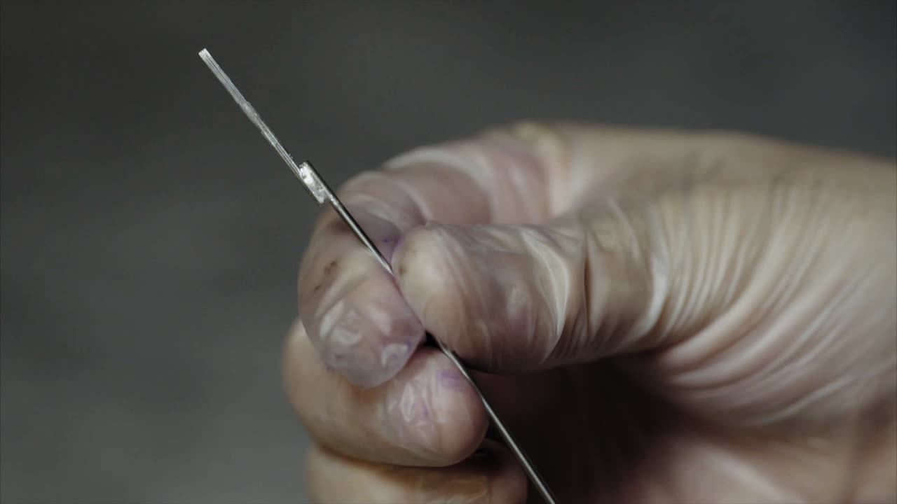 рука с хирургическим лезвием в перчатке