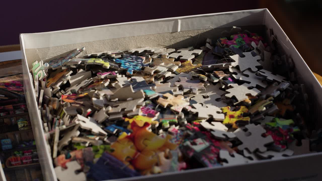 Jigsaw Puzzle pieces in their box in morning light. Handheld slow motion.
