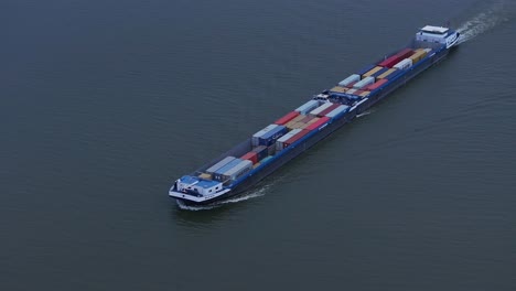 cargo vessel loaded with intermodal containers navigating on the river in netherlands