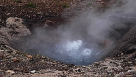 vista de ángulo amplio del burbujeo de litli-geysir, vapor saliendo del agua caliente