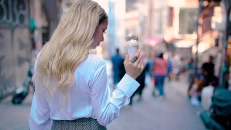 slow motion:young beautiful girl eats ice cream while walking at narrow street in europe