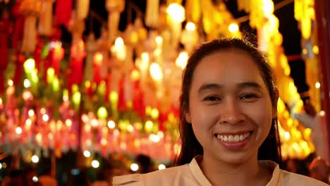 happy asian woman standing over light from thai lanna lanterns background at night in yi peng festival.