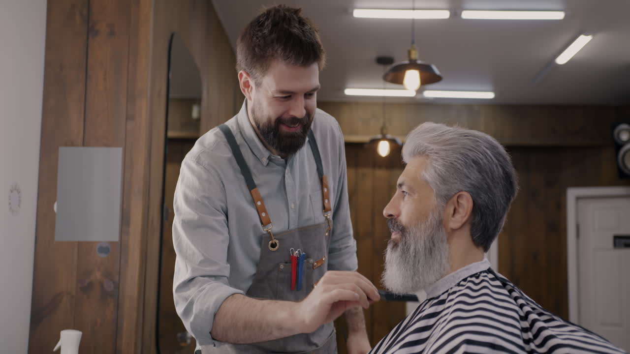 Barber grooming a senior customer's beard