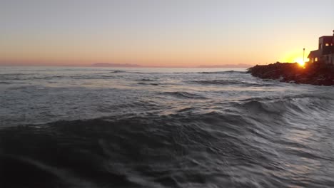 drone footage flying backwards over the ocean at sunset before zooming out