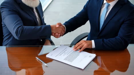 two businessmen shaking hands over a contract
