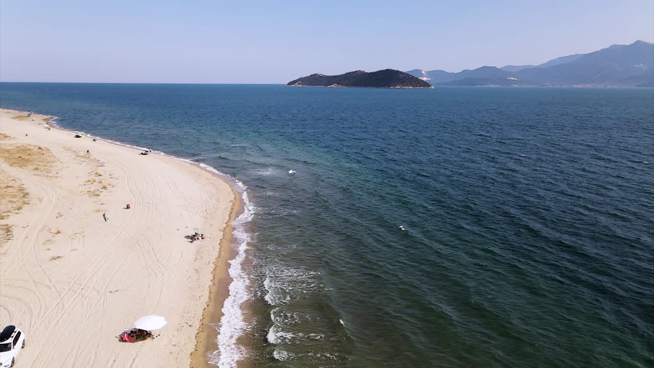 Slow motion drone clip moving backward along a tropical beach with golden sand in the area of Keramoti, Kavala, in Northern Greece in 4k