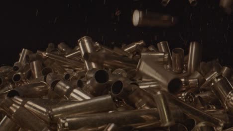 stunning slow motion of spent shell casings falling on a pile of bullet shells