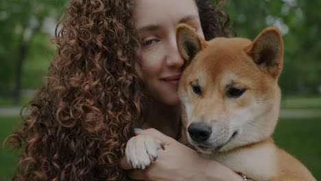 woman hugging shiba inu dog in park