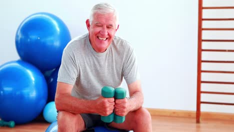 Älterer-Mann,-Der-Handgewichte-Hebt-Und-Auf-Einem-Gymnastikball-Sitzt
