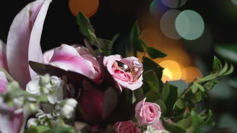 bridal bouquet designed with pink lily flower has golden wedding rings between its petals