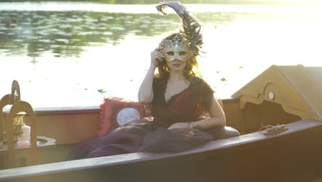 beautiful woman with carnival mask on gondola, venice, italy.