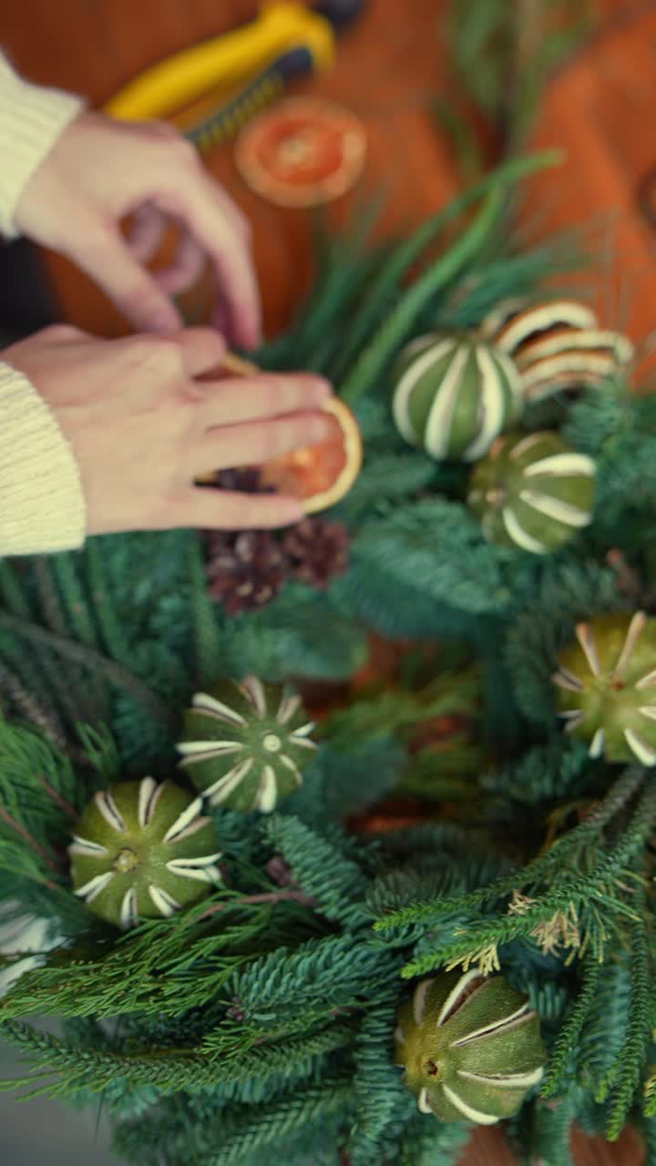 haciendo una corona de navidad con naranjas secas y conos de pino