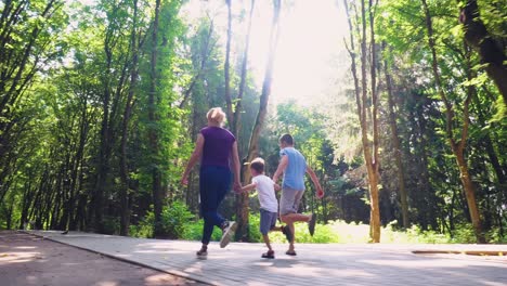 a family of three runs along an alley in the park 03