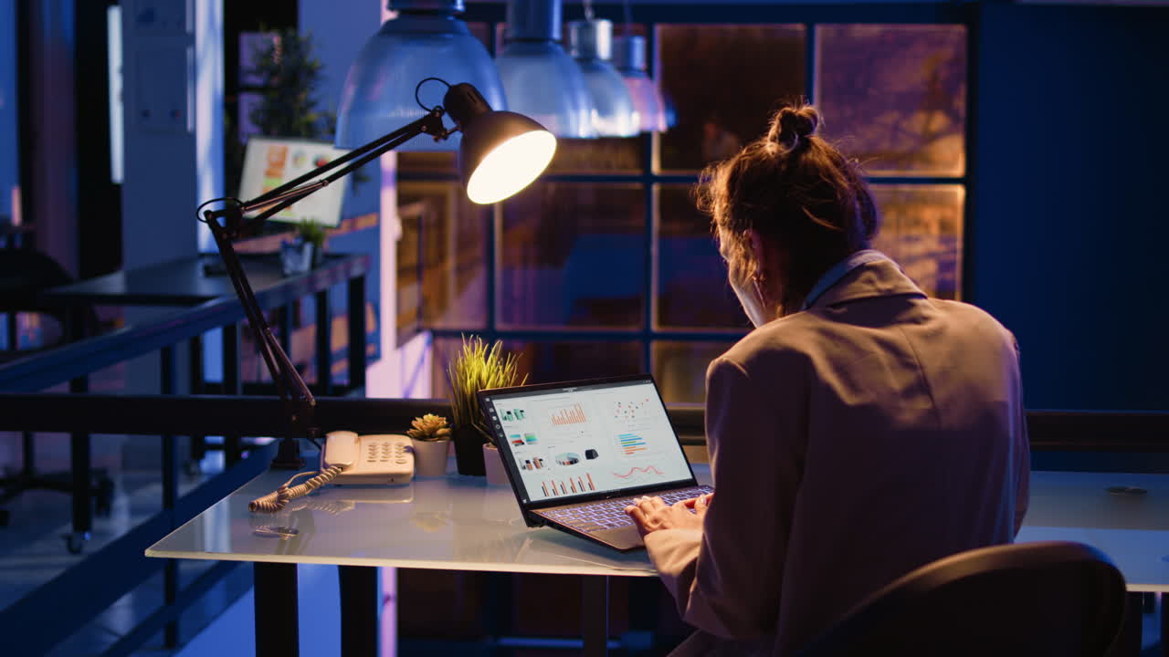 Woman working on data analysis on a laptop in an office at night