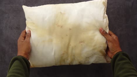 dirty pillow held in hands