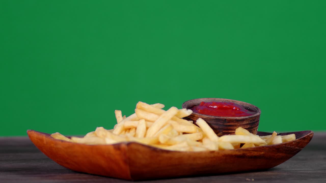 French fries on a wooden plate with tomato sauce slowly rotates.