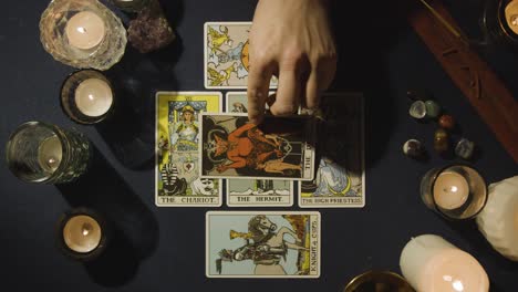 overhead shot of person giving tarot card reading laying down cards on table with candles and crystals 4