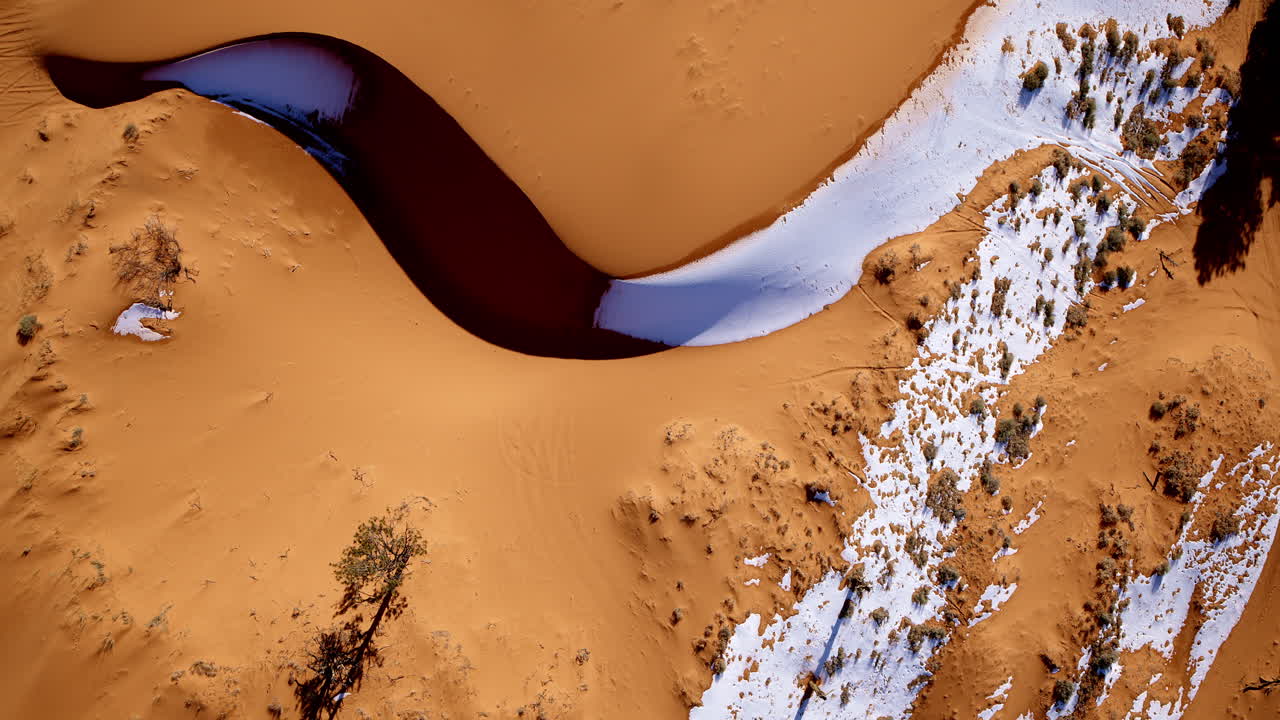 Drone shot looking straight down at pink sand dunes with all sorts of interesting colors and shapes in southern Utah.
