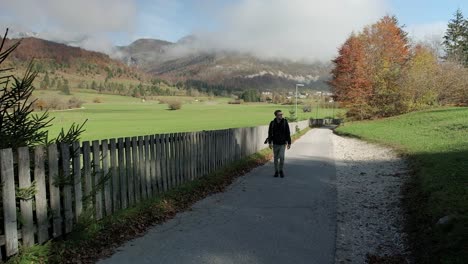 Mann-Geht-Auf-Einem-Weg-In-Richtung-Kamera-Und-Trägt-Dunkle-Kleidung,-Umgeben-Von-Herbstfarben